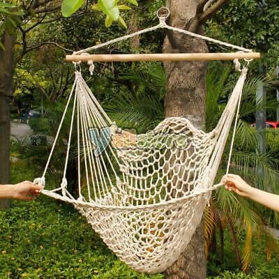 Two people holding a hammock hanging from a tree.
