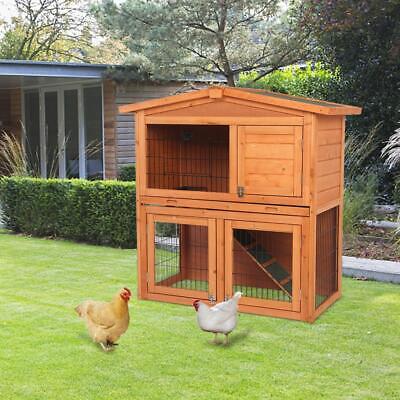 A wooden chicken coop with two chickens in the yard.