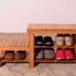 A wooden shoe rack with several pairs of shoes on it.