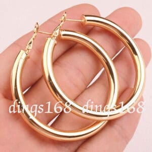 A pair of gold hoop earrings in a person's hand.