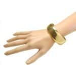 A mannequin's hand with a gold bangle bracelet.