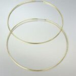 A pair of gold hoop earrings on a white surface.