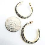 A pair of gold hoop earrings next to a quarter.