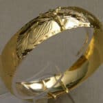 A gold plated bangle with a design on it.