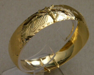 A gold plated bangle with a design on it.