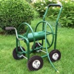 A green watering hose on a lawn.