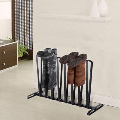 A metal shoe rack with four pairs of boots on it.
