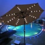 A pool with a lit umbrella.