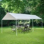 A white tent with a table and chairs in a grassy area.