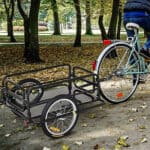 A person riding a bicycle with a cart.