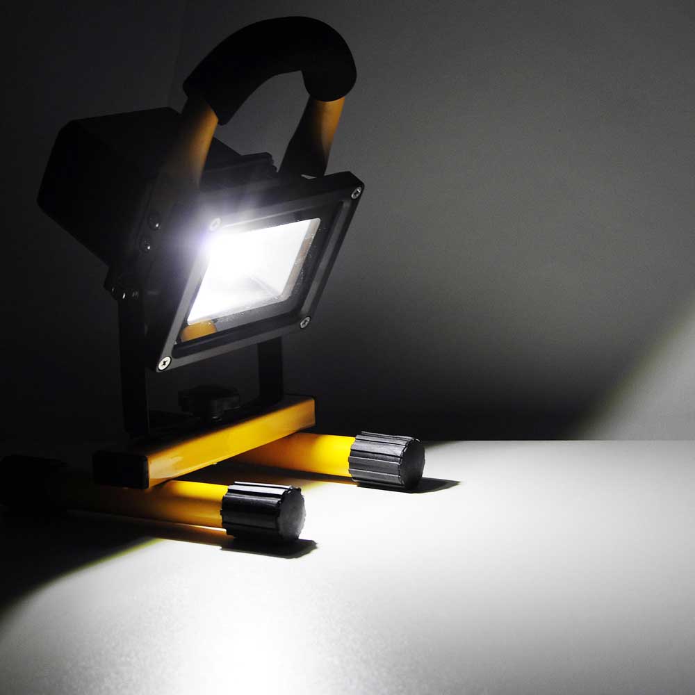 A small led flood light on a table in the dark.