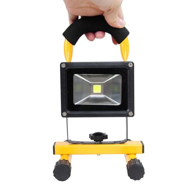 A hand holding a portable led work light.