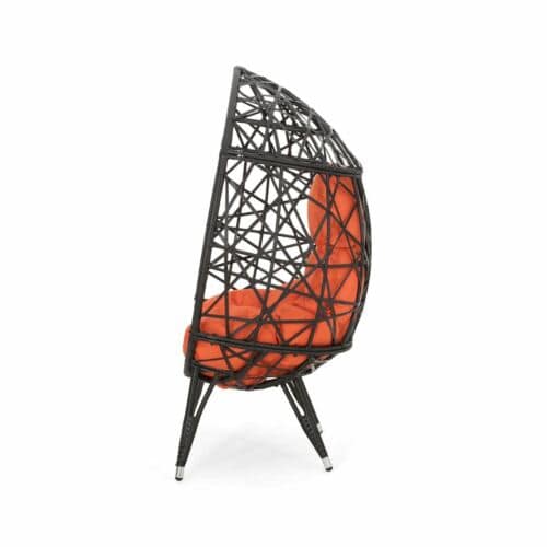 A black rattan chair with an orange cushion.