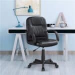 A black office chair in front of a white desk.