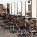 A hair salon with many chairs and mirrors.