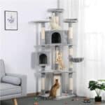 Three cats playing on a multi-level cat tree in a living room.