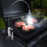 A bbq grill with steaks on it.