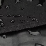 Water droplets on a black waterproof fabric surface.