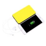 Smartphone connected to a yellow portable power bank with charging indicator on the screen.