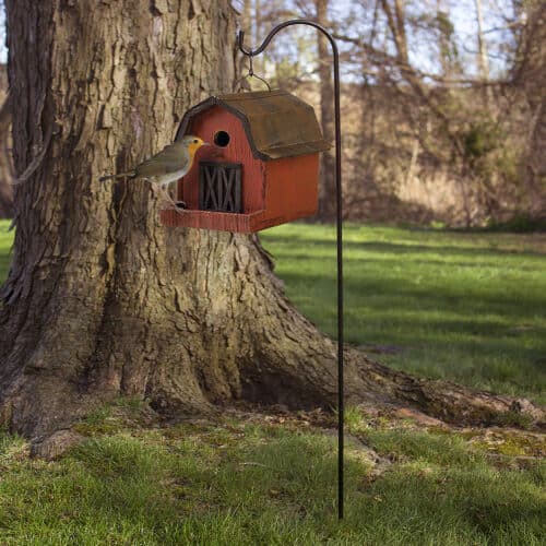 A birdhouse on a pole near a tree.
