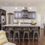 Modern kitchen interior with dark wood cabinetry, stone countertops, and bar-style seating.