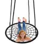 A young girl laying on a black spider web swing.