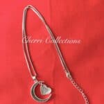 A silver necklace with a crescent and a heart on it.