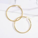 A pair of gold hoop earrings on a white surface.