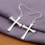 A pair of silver cross earrings on a cloth.