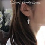 A woman wearing a pair of earrings with a cross on them.