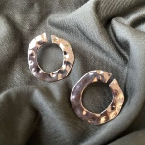 Two hammered hoop earrings on a green cloth.