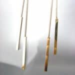 A pair of gold bar earrings hanging from a string.