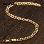 A gold plated chain bracelet on a wooden table.