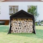 A black tarp with logs in it in front of a house.