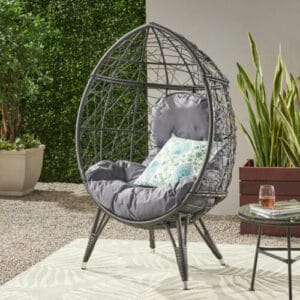 A black rattan hanging chair on a patio.