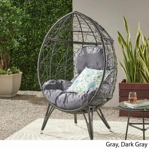 An outdoor rattan chair with a cushion and pillows.