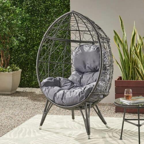 A black wicker chair with a grey cushion.