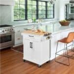 A kitchen with a white island and a wood floor.