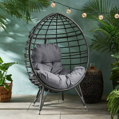 A black rattan chair in front of plants.