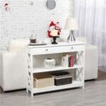 A white shelf with a lamp and a table with baskets on it.