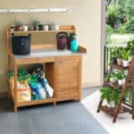 A potting bench with potted plants on a shelf.