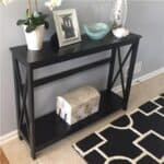 A black console table with a black and white rug.