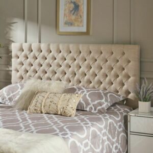 A bedroom with a beige upholstered headboard.