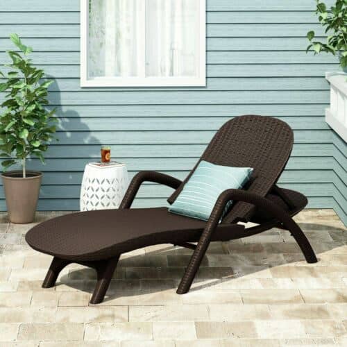 A brown wicker chaise lounge on a patio.