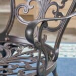 An ornate wrought iron chair on a blue rug.