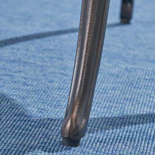 A close up of a metal chair leg on a blue carpet.