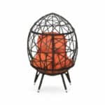 A black and orange rattan chair with an orange cushion.