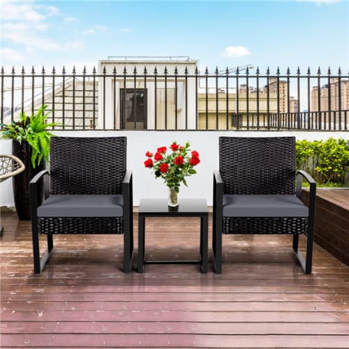 A black wicker patio furniture set on a wooden deck.