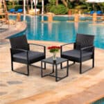 A black wicker patio furniture set next to a swimming pool.