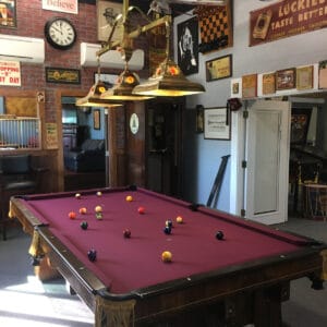 A pool table in a room decorated with vintage memorabilia and neon signs.